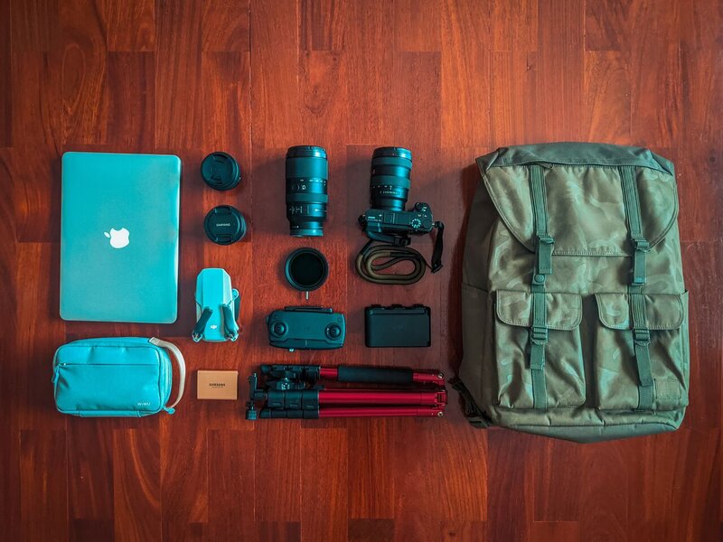  Équipement photo et autres essentiels de voyage disposés sur un plancher en bois.