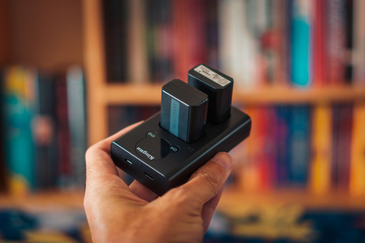 A man holding a battery charger for Sony NP-FW50 batteries