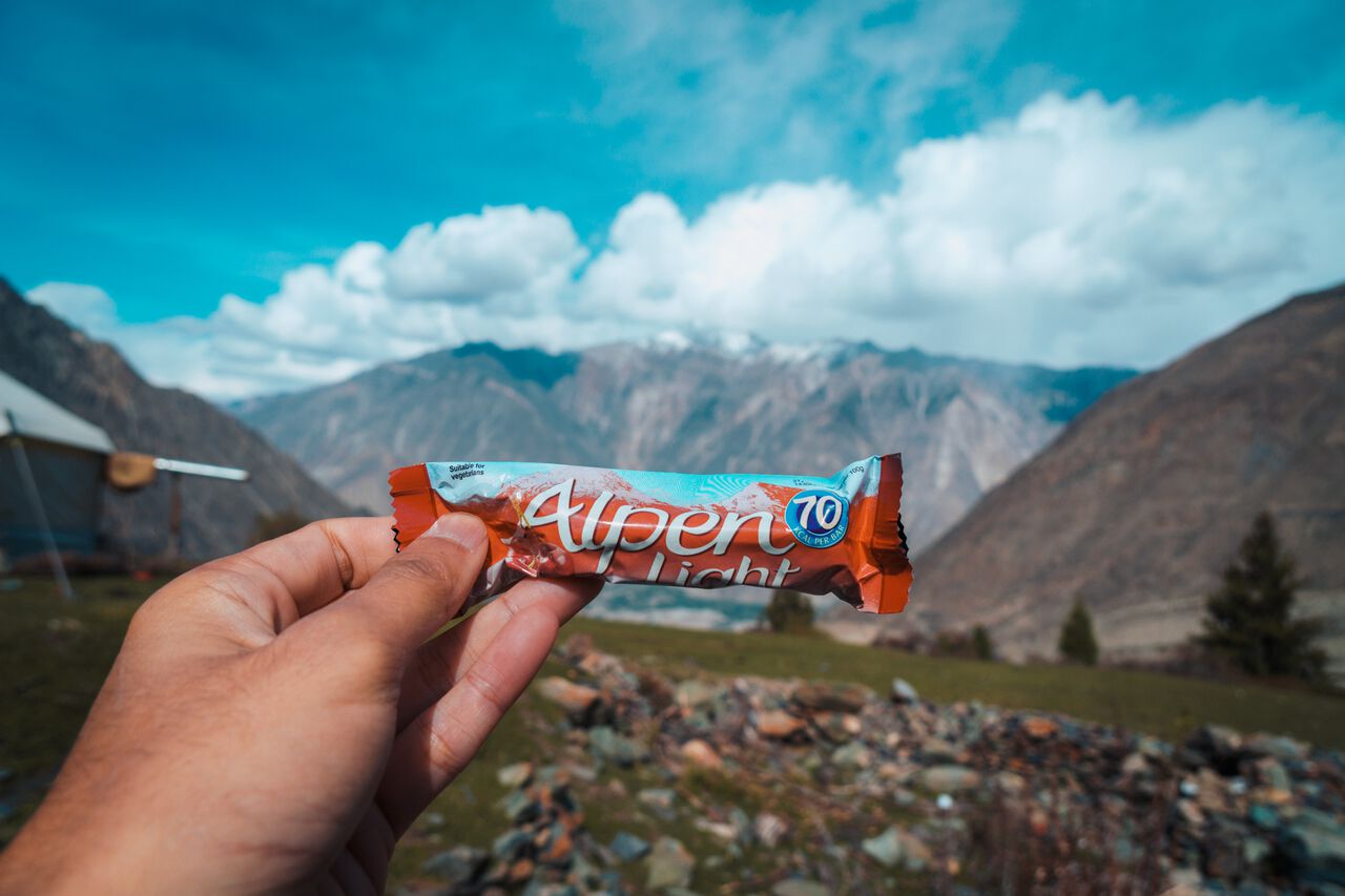 A person holding an Alpen Energy Bar while hiking in Pakistan