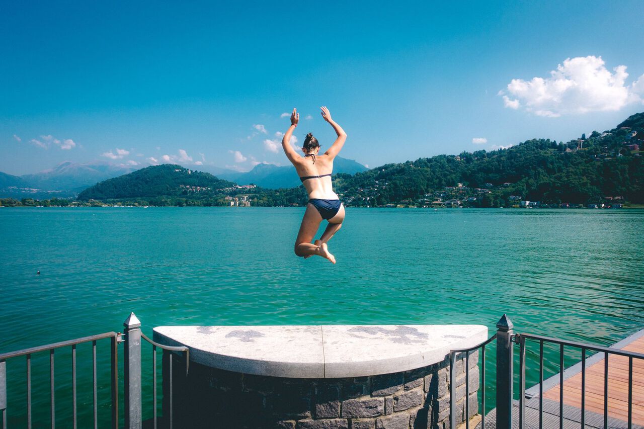 A woman jumping into the water in Lugano Lake in Switzerland