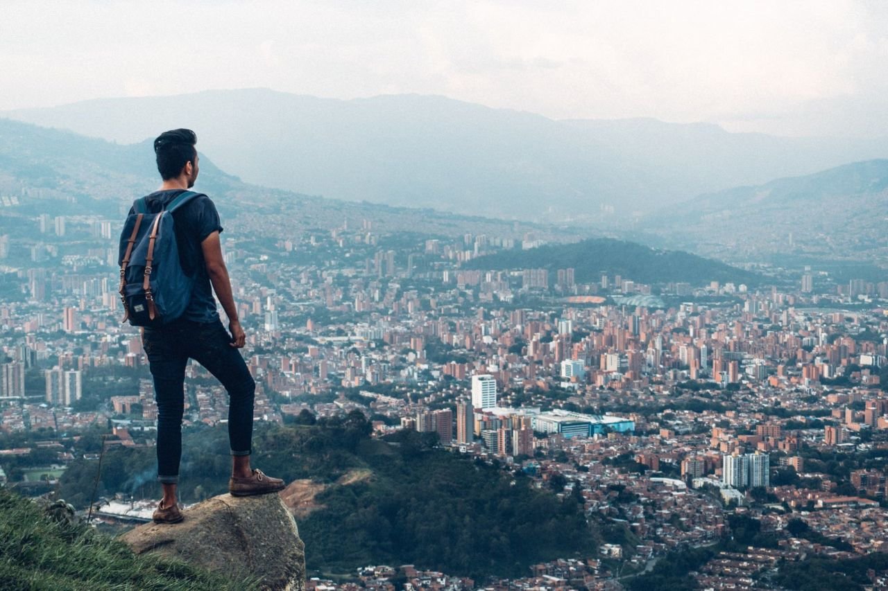 A person with a backpack standing on a rock looking at the city of Medellin in Colombia, South America