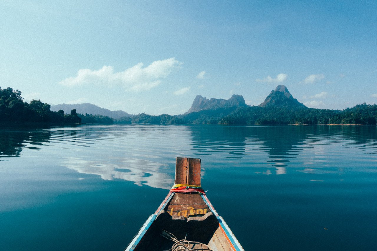 A long tail boat heading towards a mountain in Khao Sok Lake, Thailand