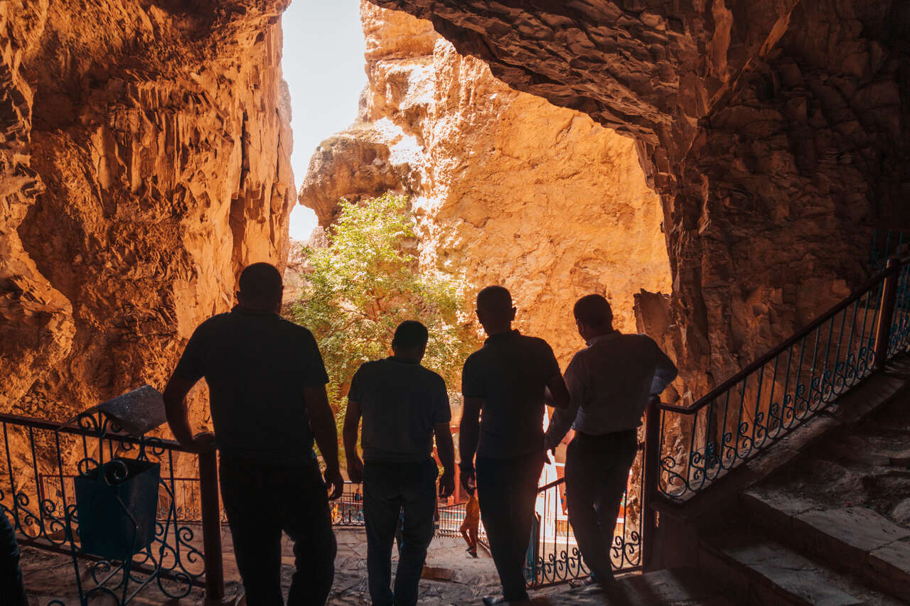 4 men walking down the stairs in Ashab-i Kehf Cave in Nakhchivan, Azerbaijan.