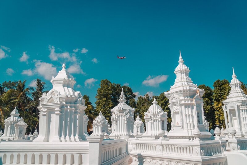 een vliegtuig dat boven de witte pagodes van Wat Suan Dok vliegt in Chiang Mai, Thailand.