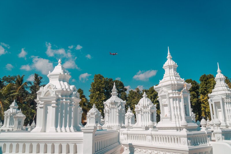  Un avión volando sobre las pagodas blancas de Wat Suan Dok en Chiang Mai, Tailandia.