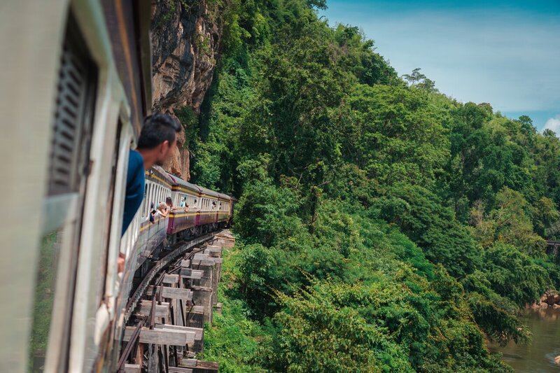 en rejsende kigger ud fra et tog på Dødsbanen i Kanchanaburi, Thailand