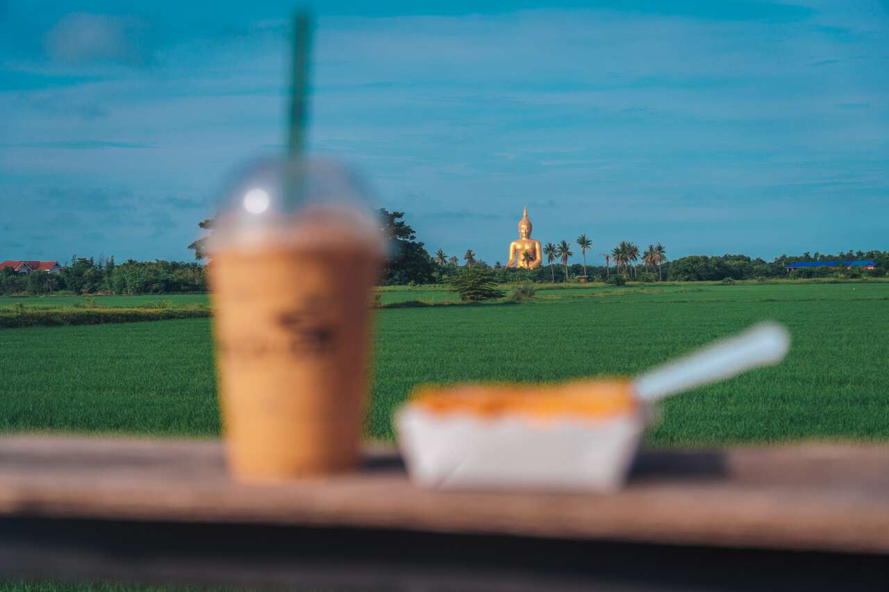 The view from the Lao Cafe by a rice field with the Great Buddha of Thailand in the background.