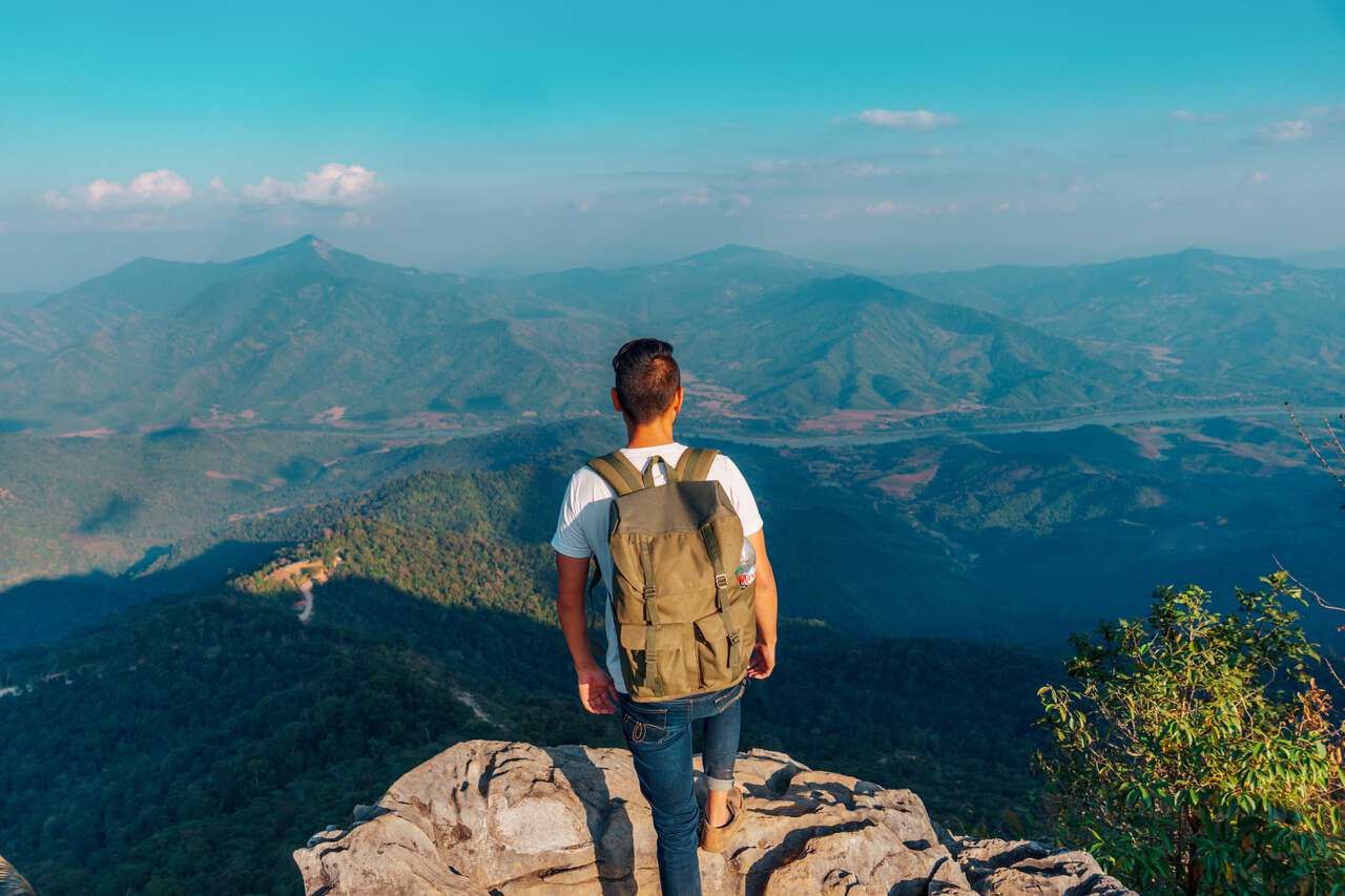 A person looking over the rocks at Laos from Doi Pha Tang viewpoint in Chiang Rai