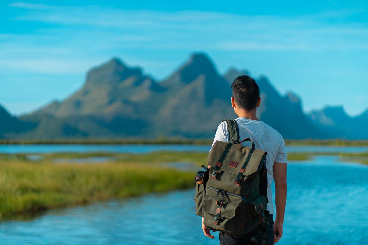 A person with a backpack looking tat Sam Roi Yot mountain from a far in Hua Hin, Thailand