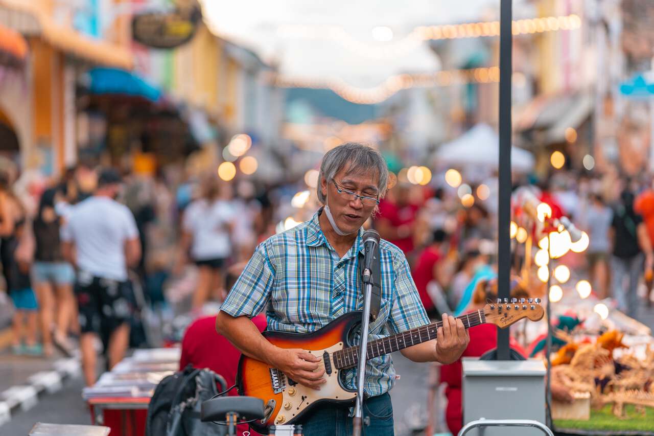 A person playing a guitar in Phuket shot with an Sigma 85mm F1.4 lens.