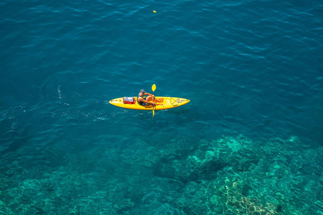 A man and a kayak on a crystal clear water