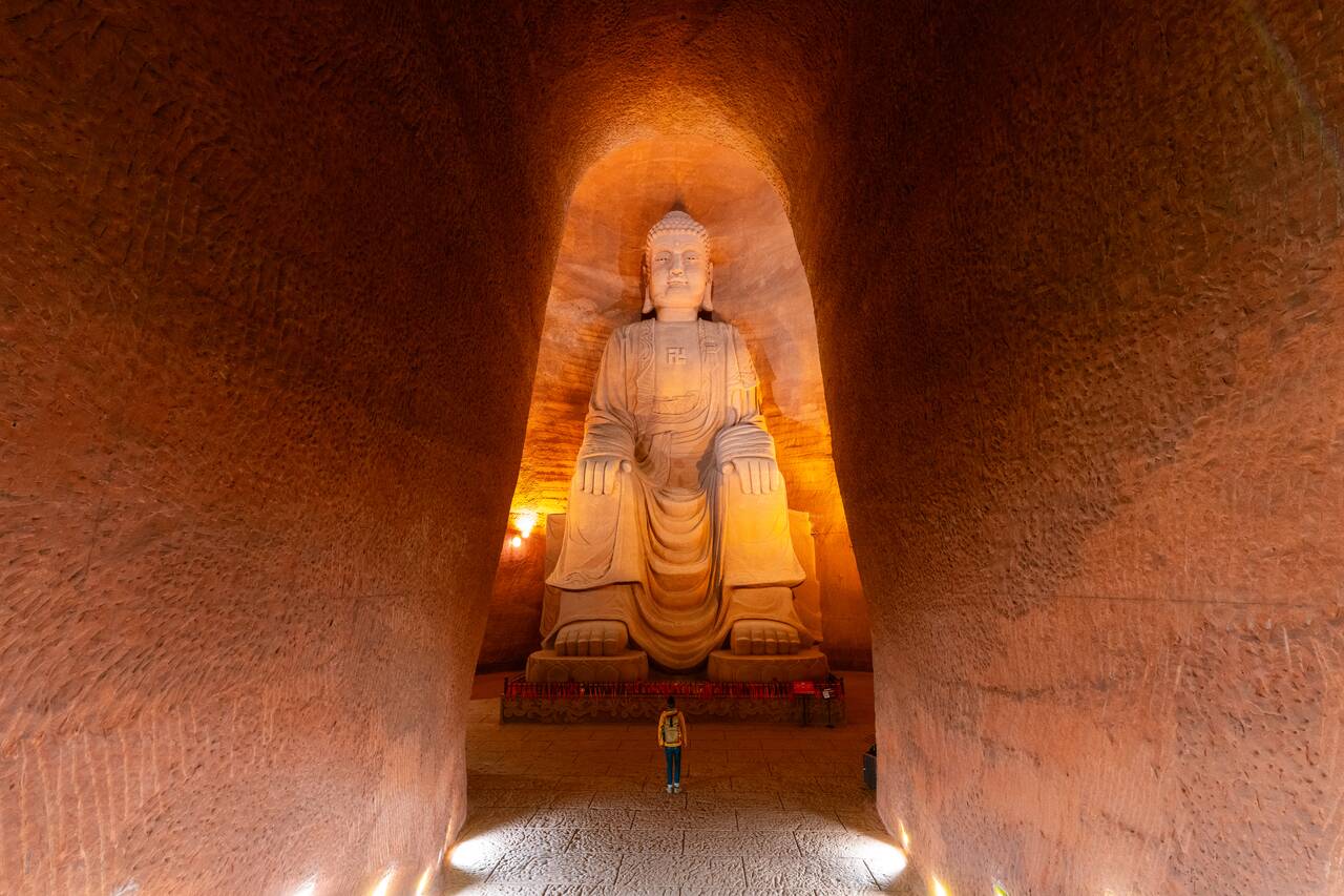 Me standing in front of a giant seated buddha image at Oriental Buddha Park
