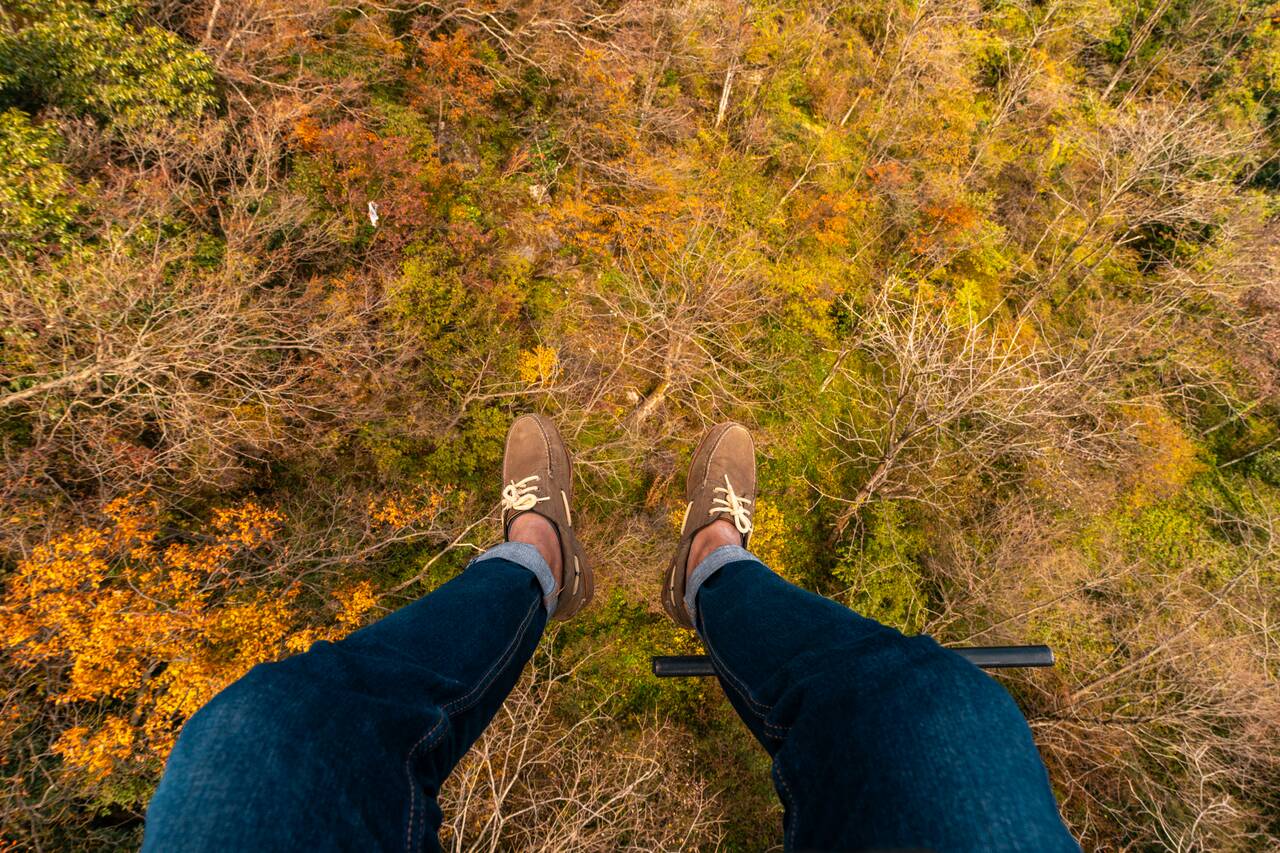 My legs hanging over a forest while on a cable car to Tianmen Temple