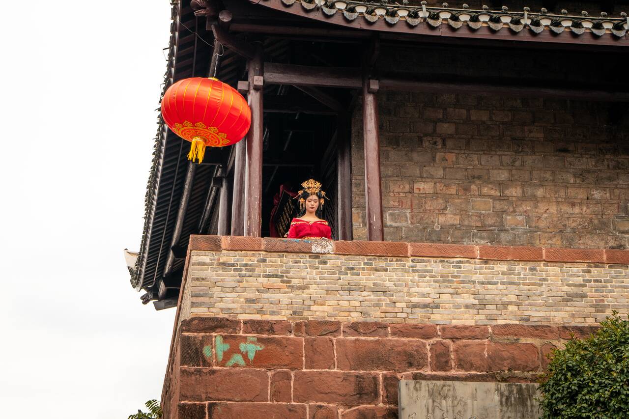 A woman standing at the gate of Fenghuang