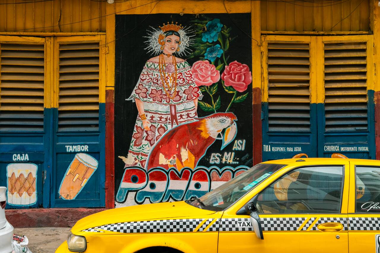 Colorful murals with a taxi parked in front of it in Panama City