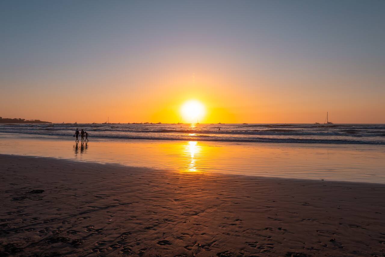 a couple walking along the beach at sunset