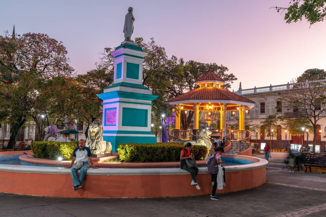 People sitting at a fountain in Parque Central in the Evening
