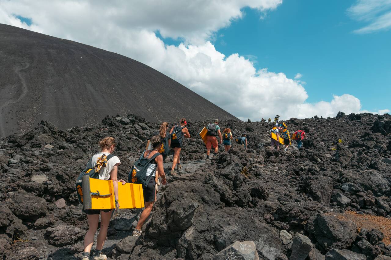 People hiking up Cerro Negro with their boards in hand