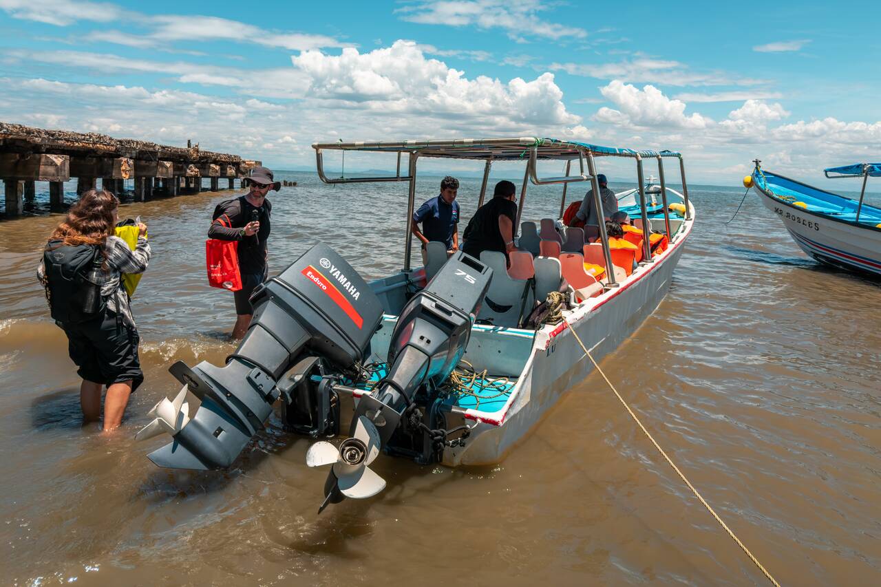 Travelers walking in the water to the speed boat to cross the border from Nicaragua to El Salvador