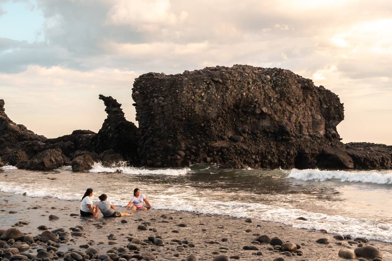 Locals hanging out at El Tunco Beach by the rock formation