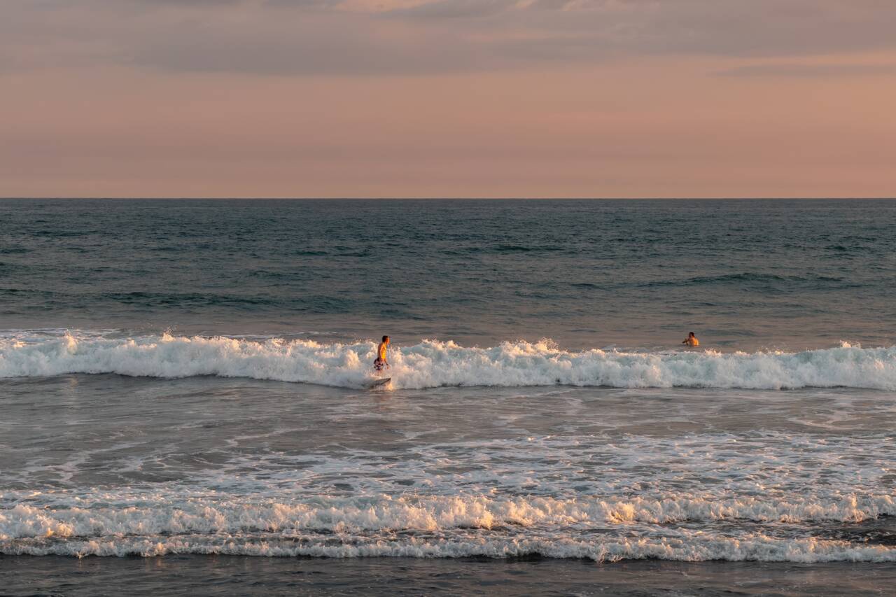People swimming at El Zonte Beach at sunset