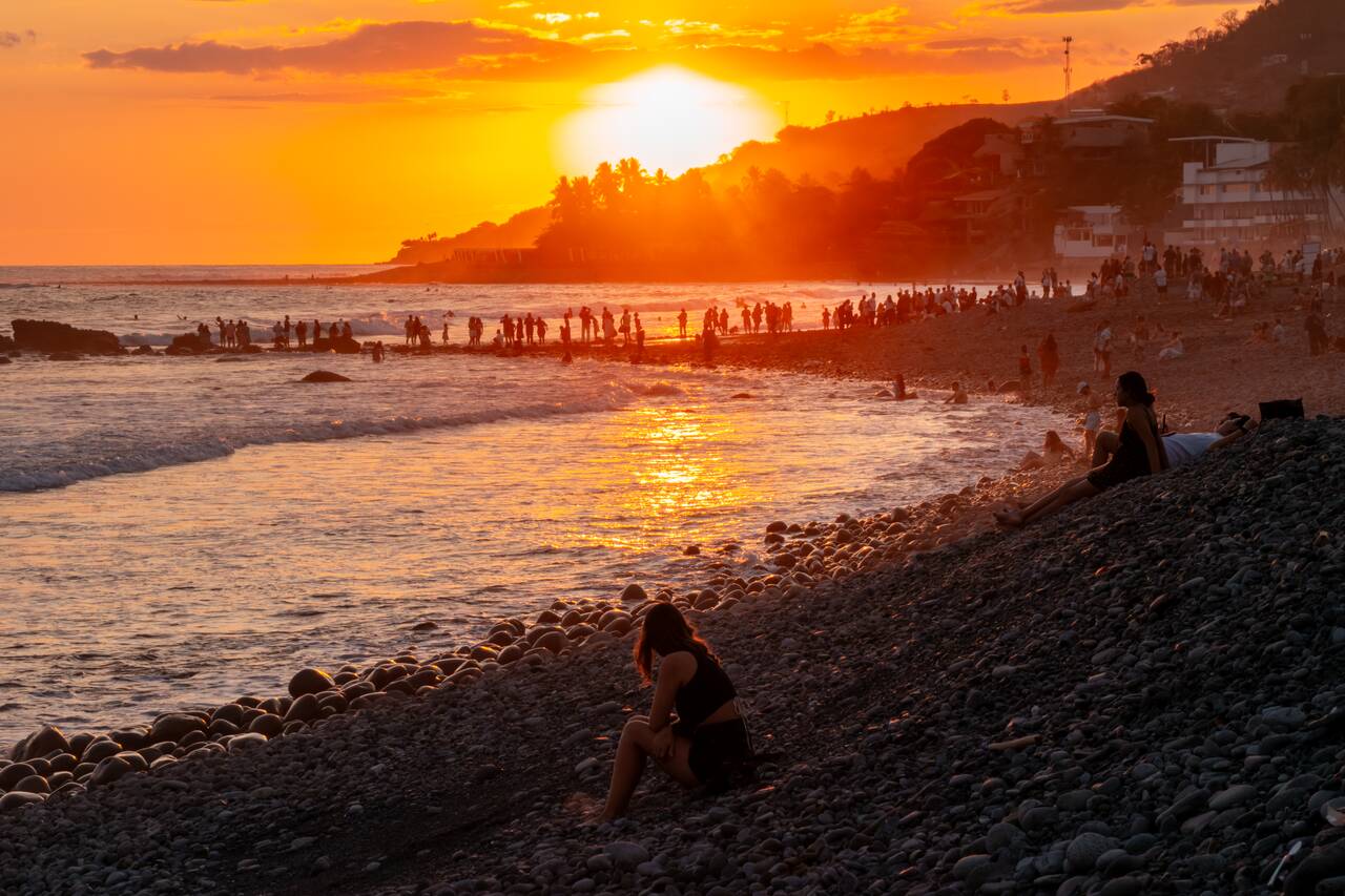 A woman sitting alone watching the sunset at El Tunco Beach