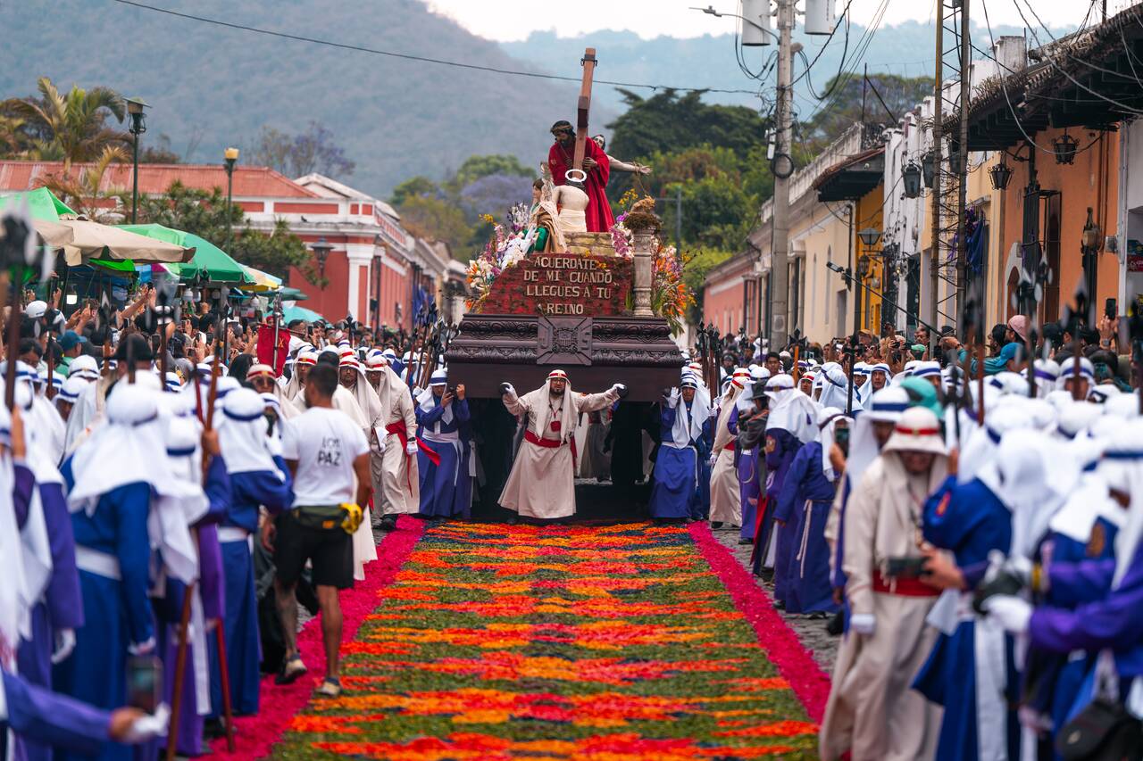 A procession going through a colorful carpet in Antigua during Semana Santa