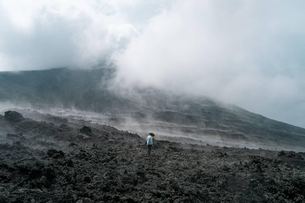 A person standing in the steam of the lava field at Pacaya Volcano