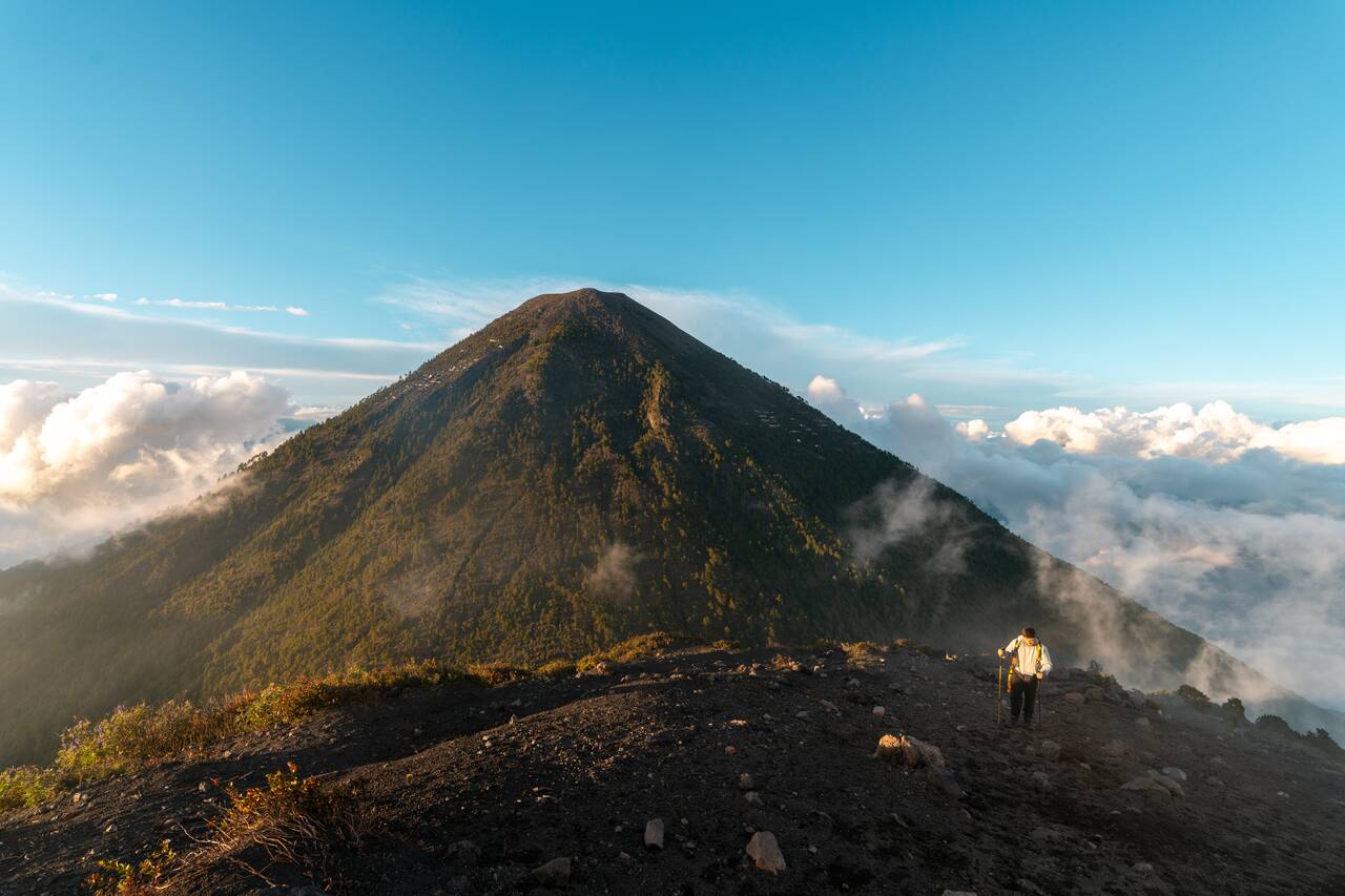 A person hiking up Fuego with Acatenango in the background