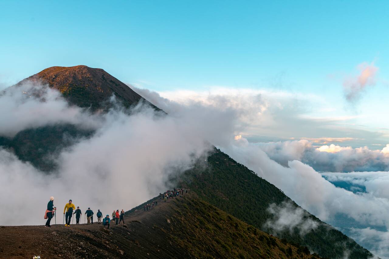 People with trekking poles hiking along a trail on Fuego
