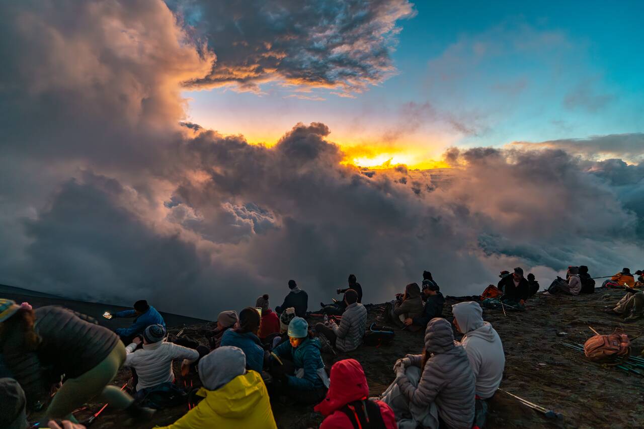 People in full winter gear watching the sunset on Fuego