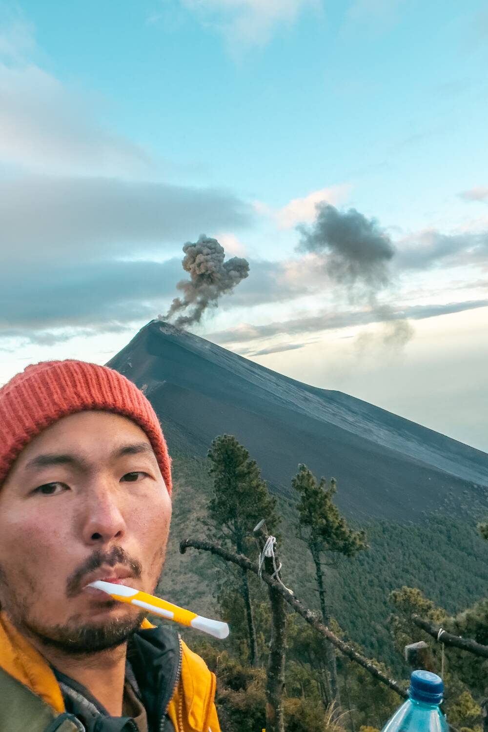 Me brushing my teeth at campsite while Fuego is erupting in the background