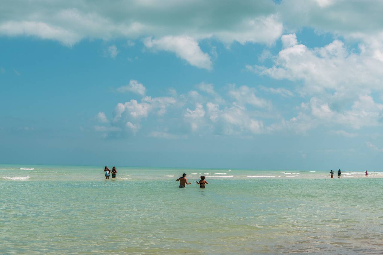 People walking along the shallow sand bank to Punta Mosquito