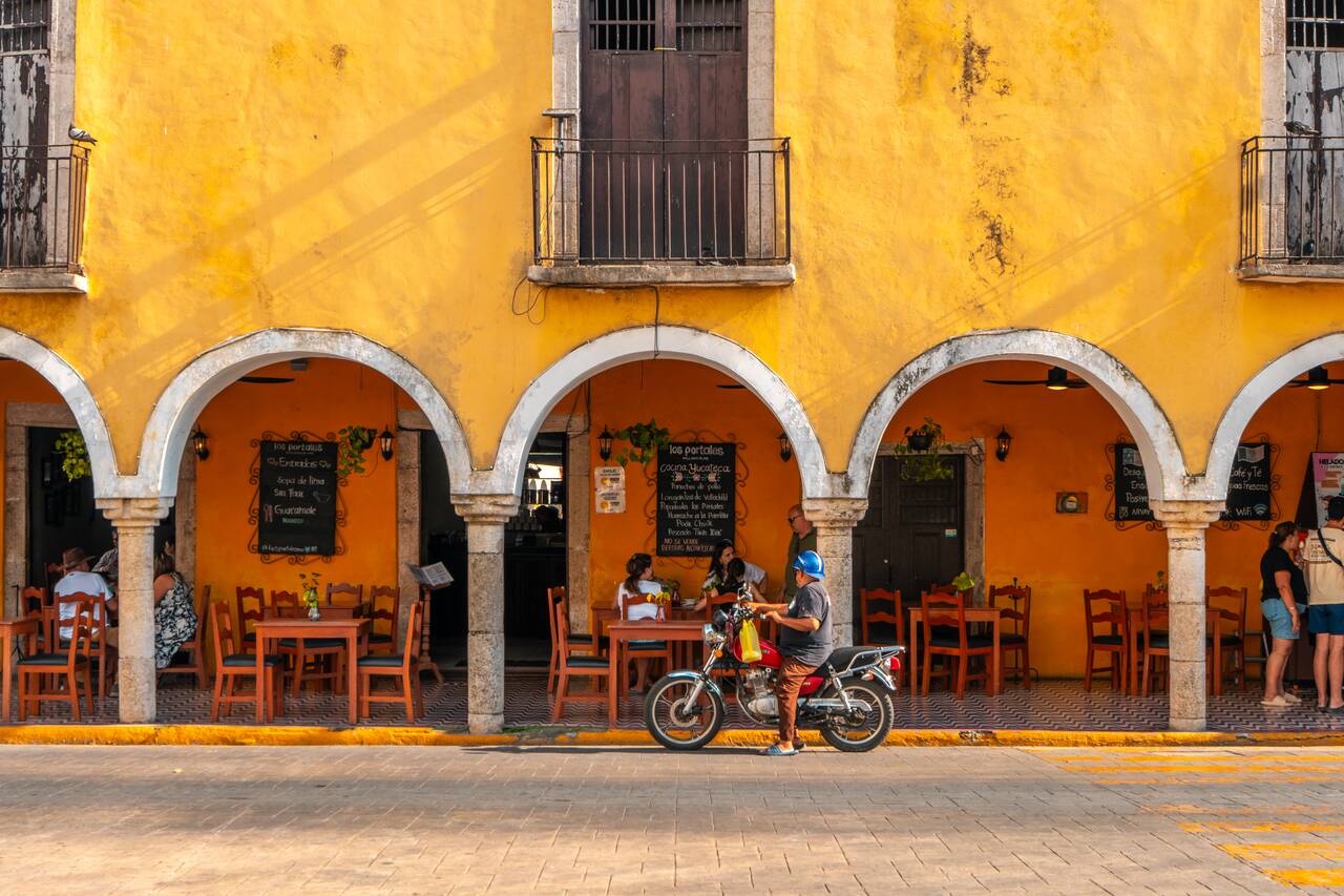 A motorbike park in front of a colonial building at arque Principal Francisco Cantón Rosado