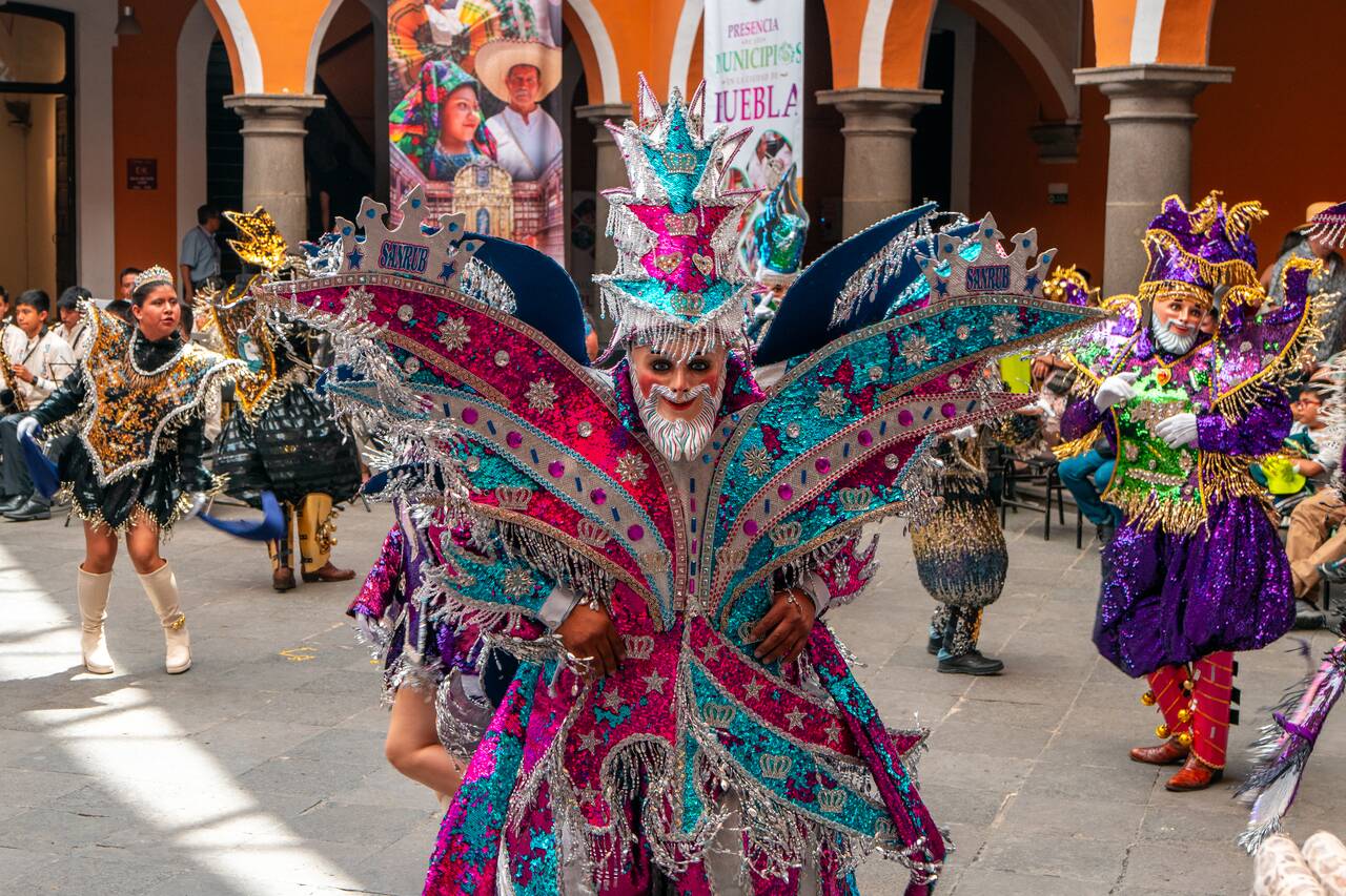 A person dressed in colorful clown dancing during the Cinco de Mayo celebration in Puebla