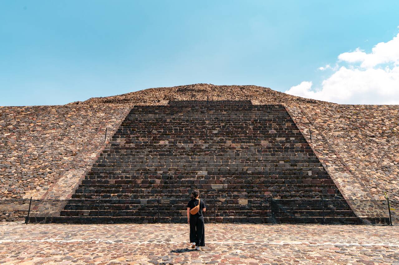 A woman standing in front of a stairs up the pyramid in Teotihuacan