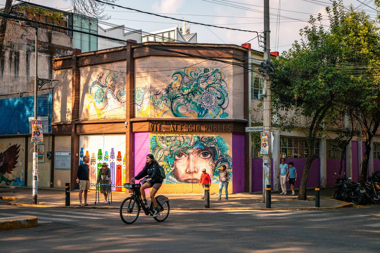 A woman biking pass a mural in Roma Norte