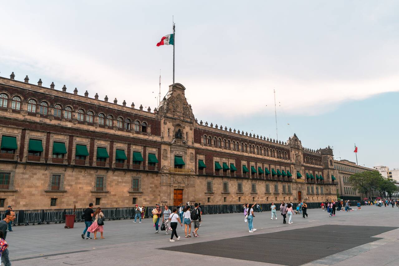 People walking by the National Palace at the Historic Center