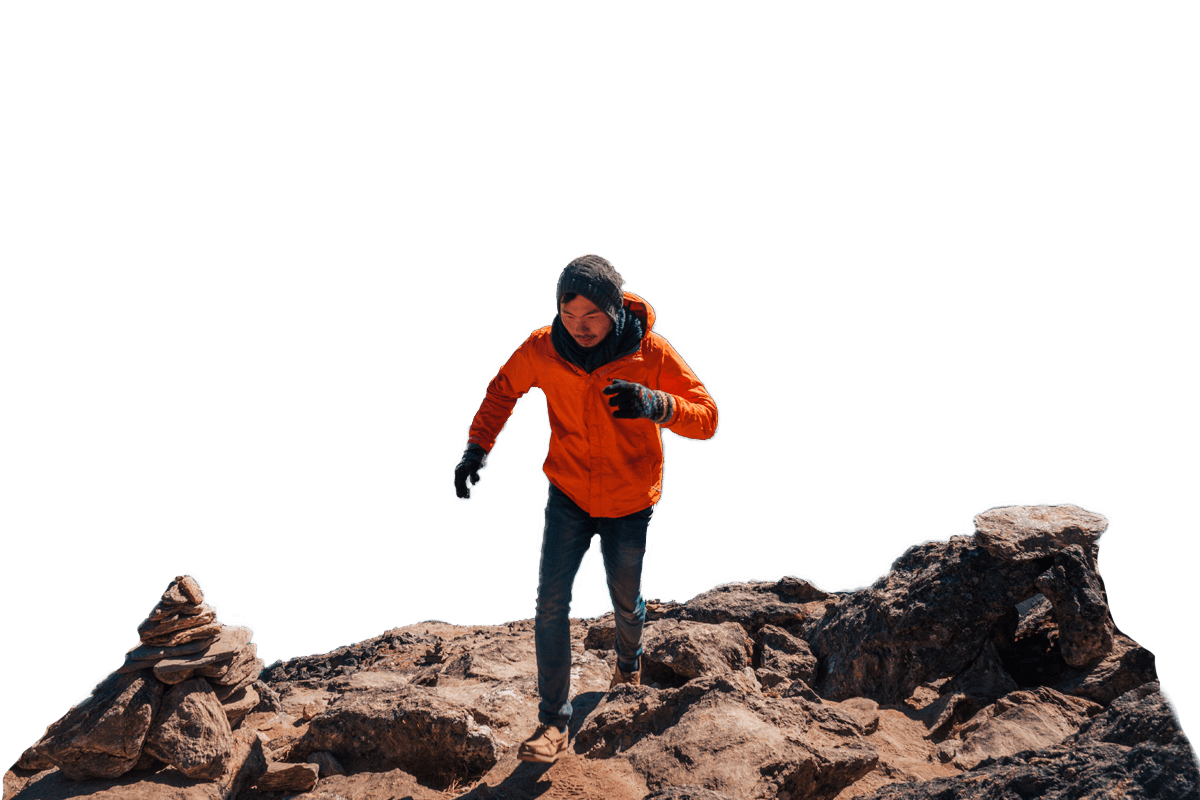 A traveler in an orange jacket hiking in the Himalayas