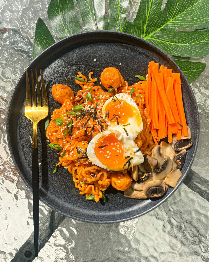 Decorate the dish with mushroom, carrot, soft boiled egg, nori flakes, sesame, and spring onion.
