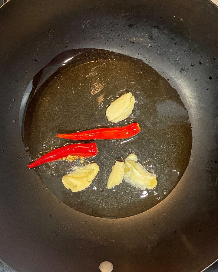 Heat the wok with medium-high heat and then add vegetable oil and chilies garlic. Cook until the garlic is aromatic and turns brown.