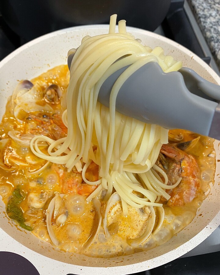 Use the tong and add the pasta and low the heat. Add some pasta boiling if you need more liquid or you can also make it as dry as you like.