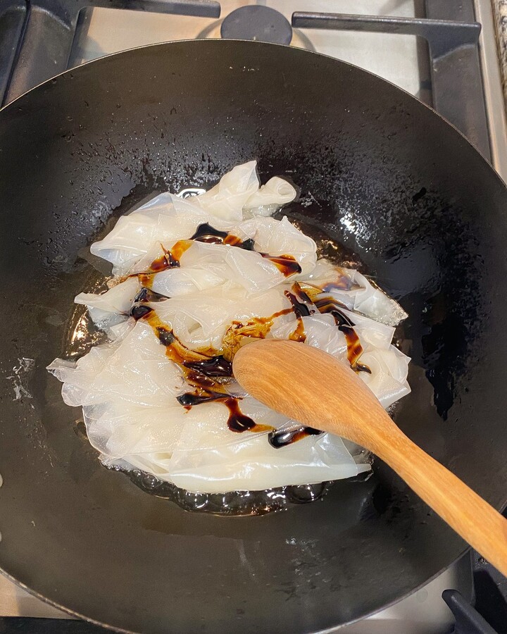 Heat a skillet or wok over high heat, add cooking oil and toss noodles in black soy sauce.
