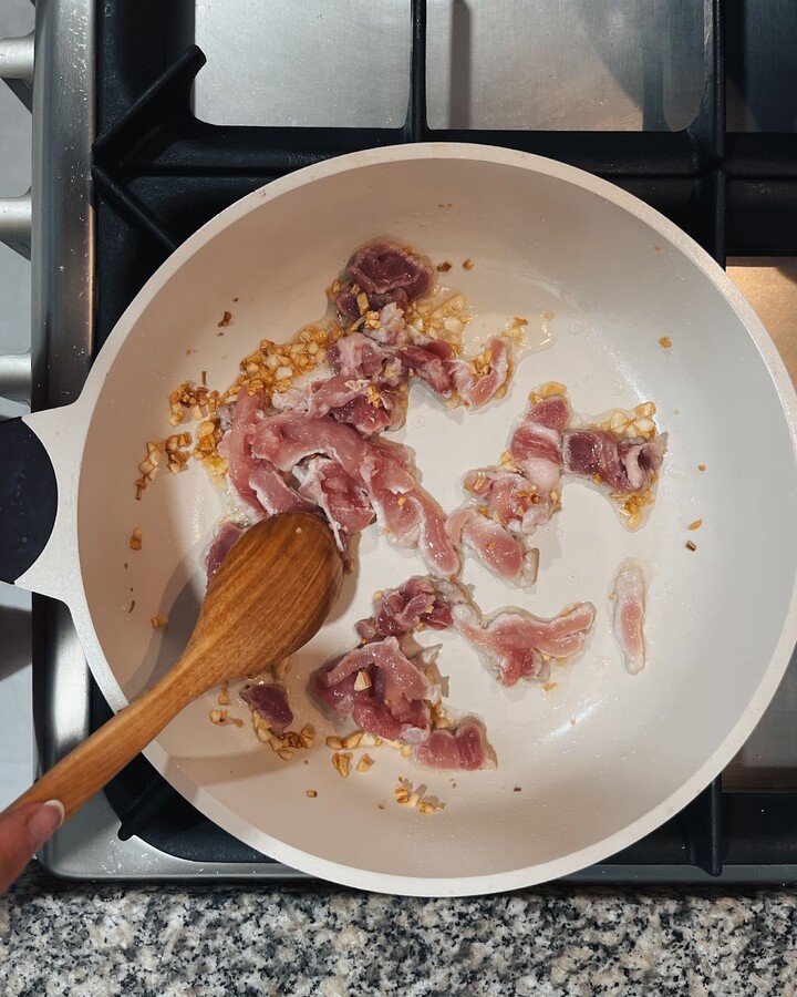 To start, heat a wok or large non-stick frying pan over medium-high heat. Add cooking oil and minced garlic to the pan. Cook for about 1 minute, or until the garlic is browned and fragrant.