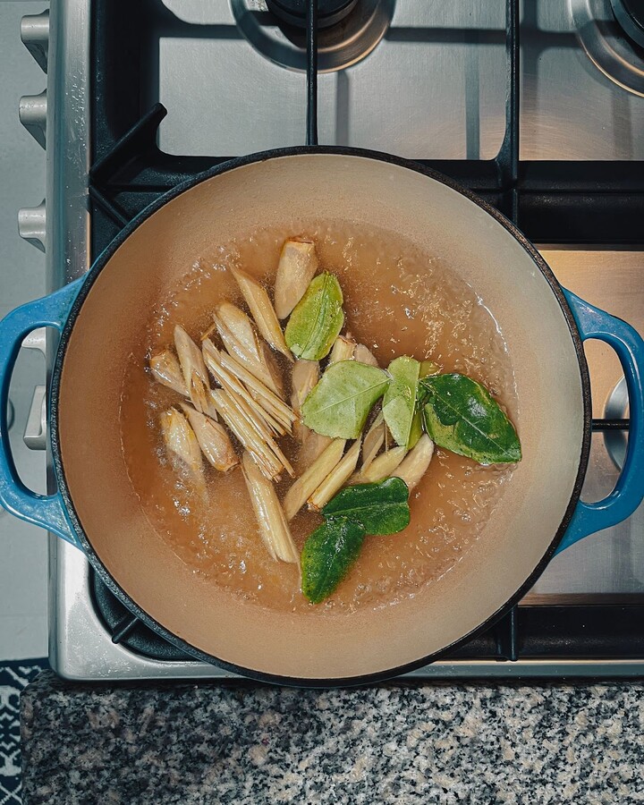 To infuse the base of the soup with aromatic flavors, add lemongrass, kaffir lime leaves, and galangal root to the pot of boiling chicken stock, along with a pinch of salt. Let the herbs boil for about 10 minutes to allow their flavors to fully infuse the broth.