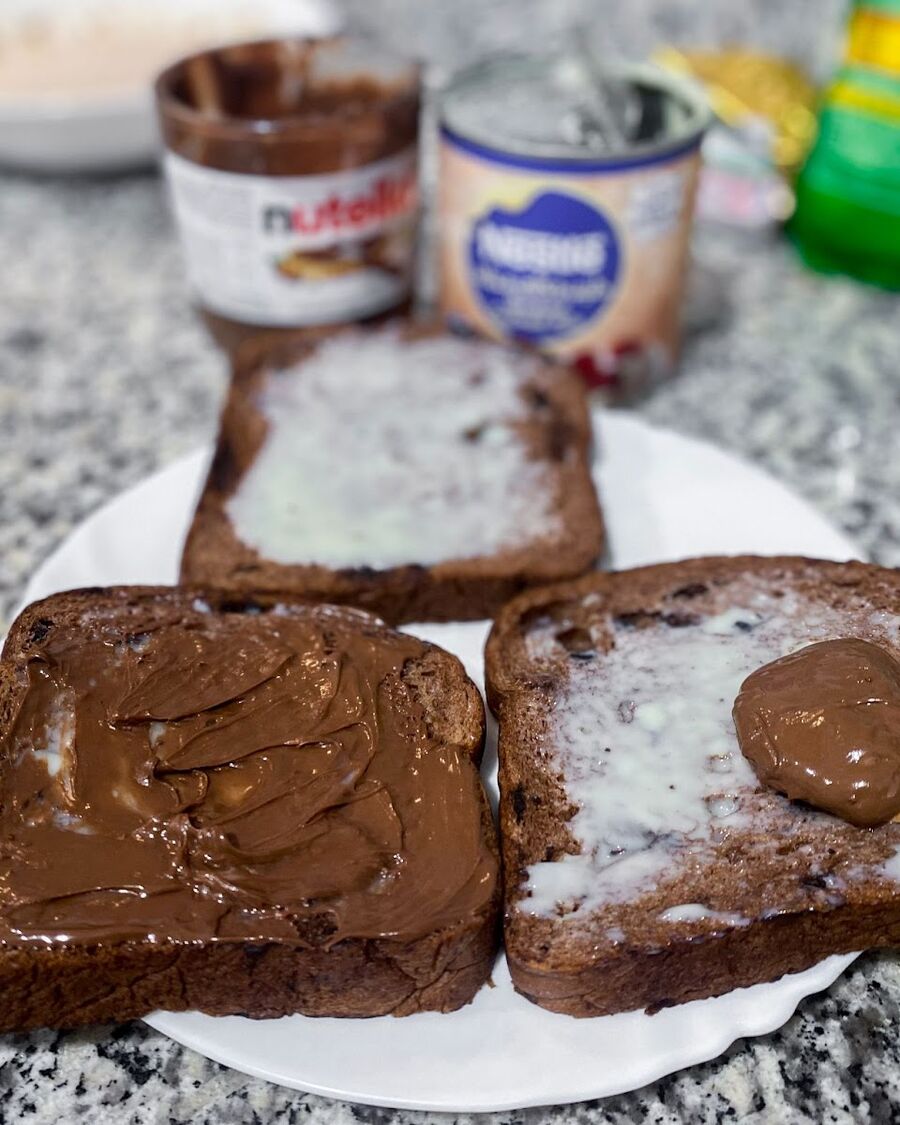 To make the filling for the toast, take 2-3 slices of bread and spread Nutella chocolate sauce and sweetened condensed milk on one side of each slice.