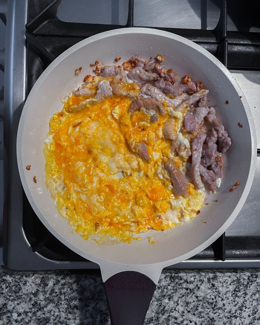 Crack an egg into the pan and scramble it until it sets.