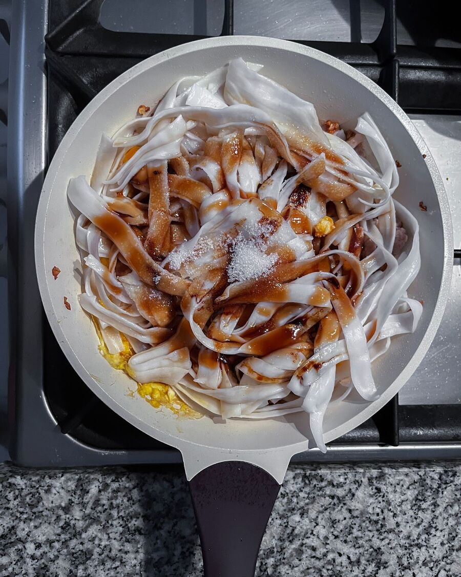 Add the fresh, flat rice noodles on top of the eggs and pork, then pour the mixed sauce over everything.
