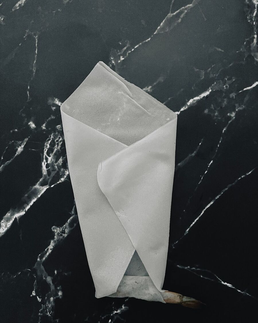 Tuck the wrapper from the bottom over the shrimp once. Then, fold the left and right sides of the wrapper towards the middle.