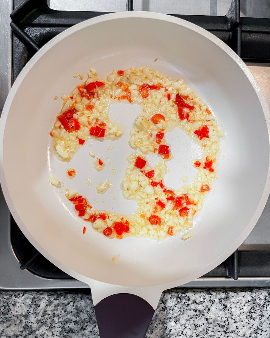 Heat a wok or pan on medium-high heat. Add cooking oil, minced chili, and garlic. Stir constantly until fragrant.